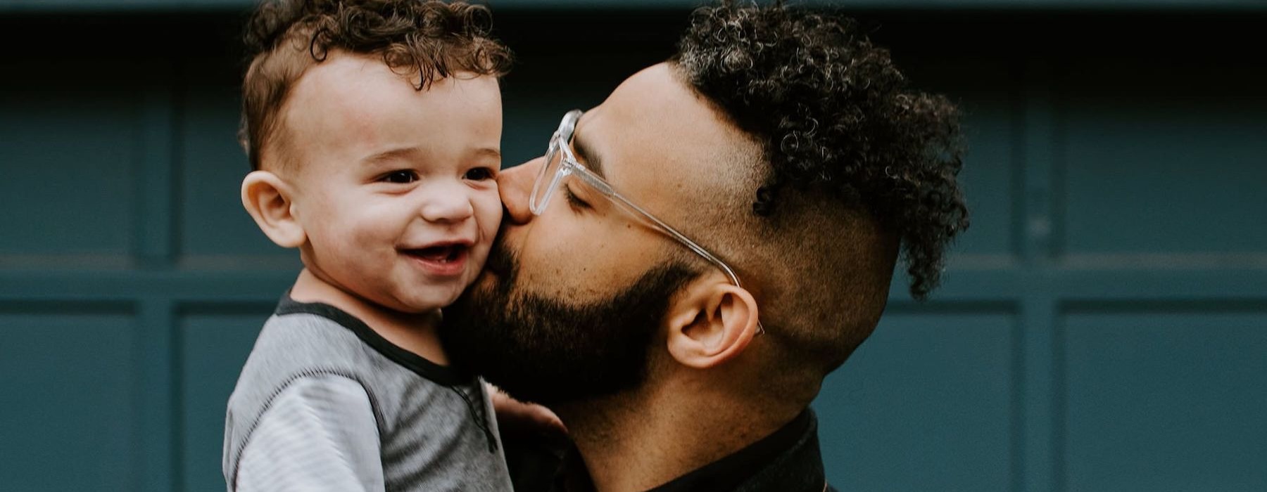 father holds and kisses his toddler son